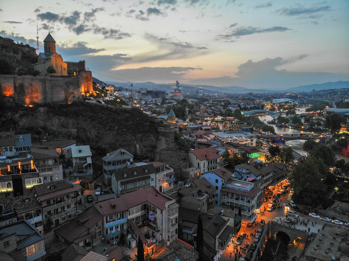 Aerial view of Tbilisi Old Town at sunset, with Metekhi Church and the Mtkvari River